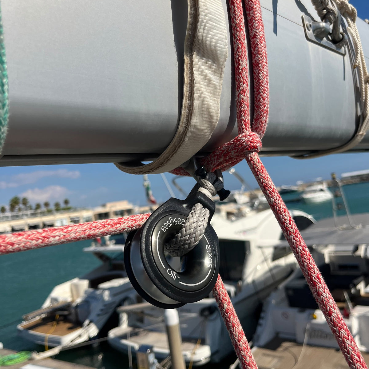 Olli snatch block fixed to the boom with a soft shackle, line running through, marina in the background