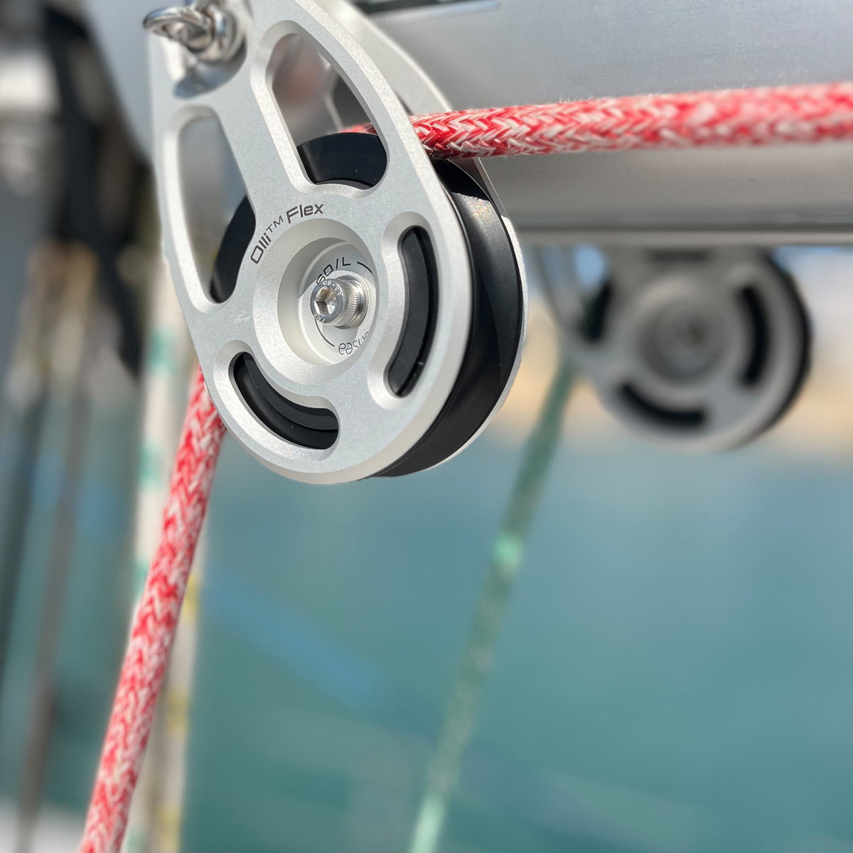 Olli Flex 60 L block hanging from the boom bail with a red sheet running through, marina in the background